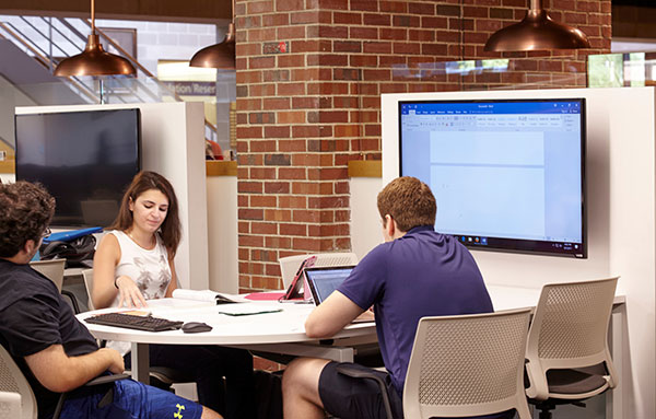 Students working at a 5-person collaboration table in the library.